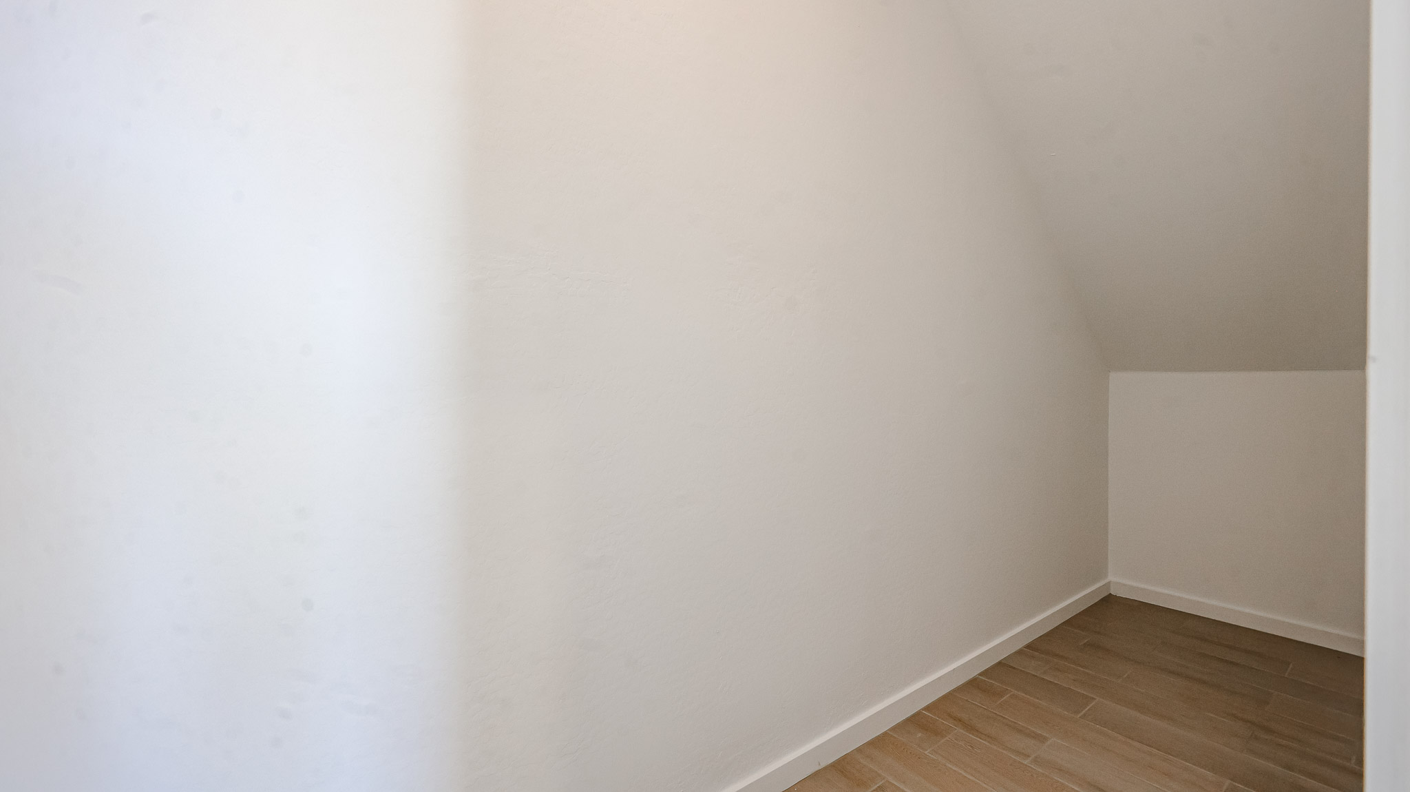 A white wall with a wood floor.