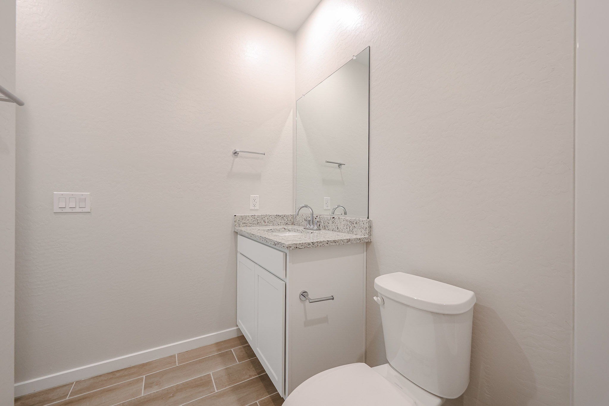 A bathroom with a sink toilet and mirror.