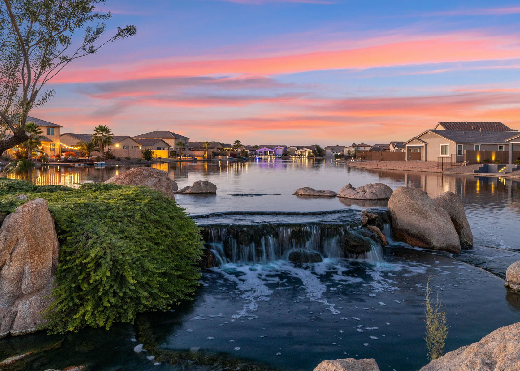 A body of water with rocks and buildings in the background.