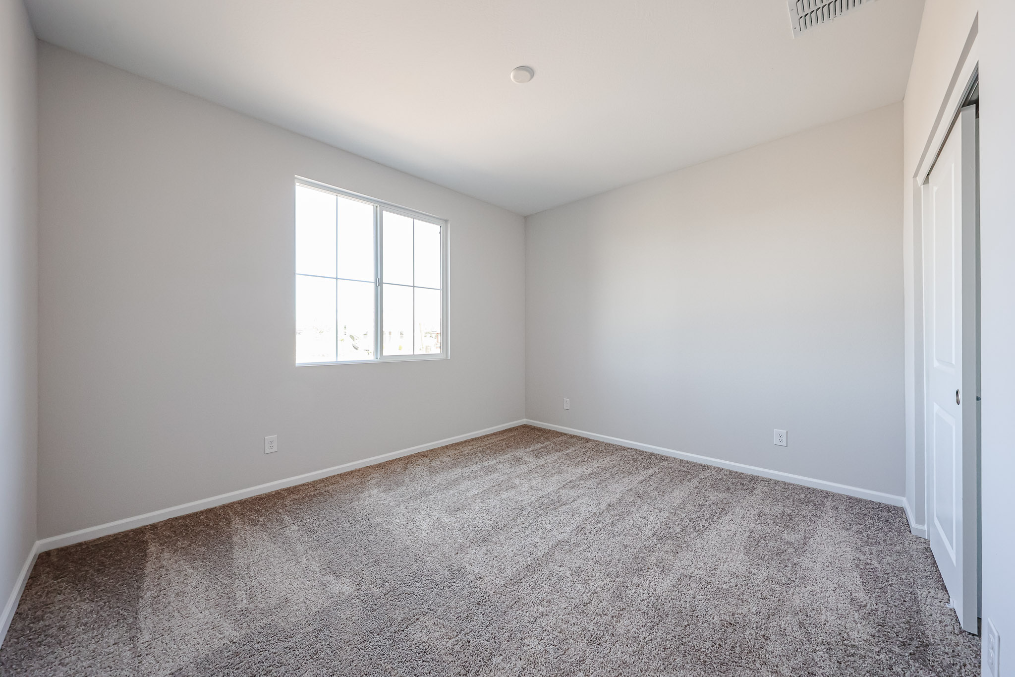 A room with a carpet and a window.