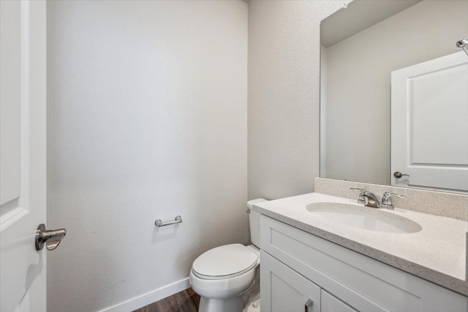 A bathroom with a sink toilet and mirror.