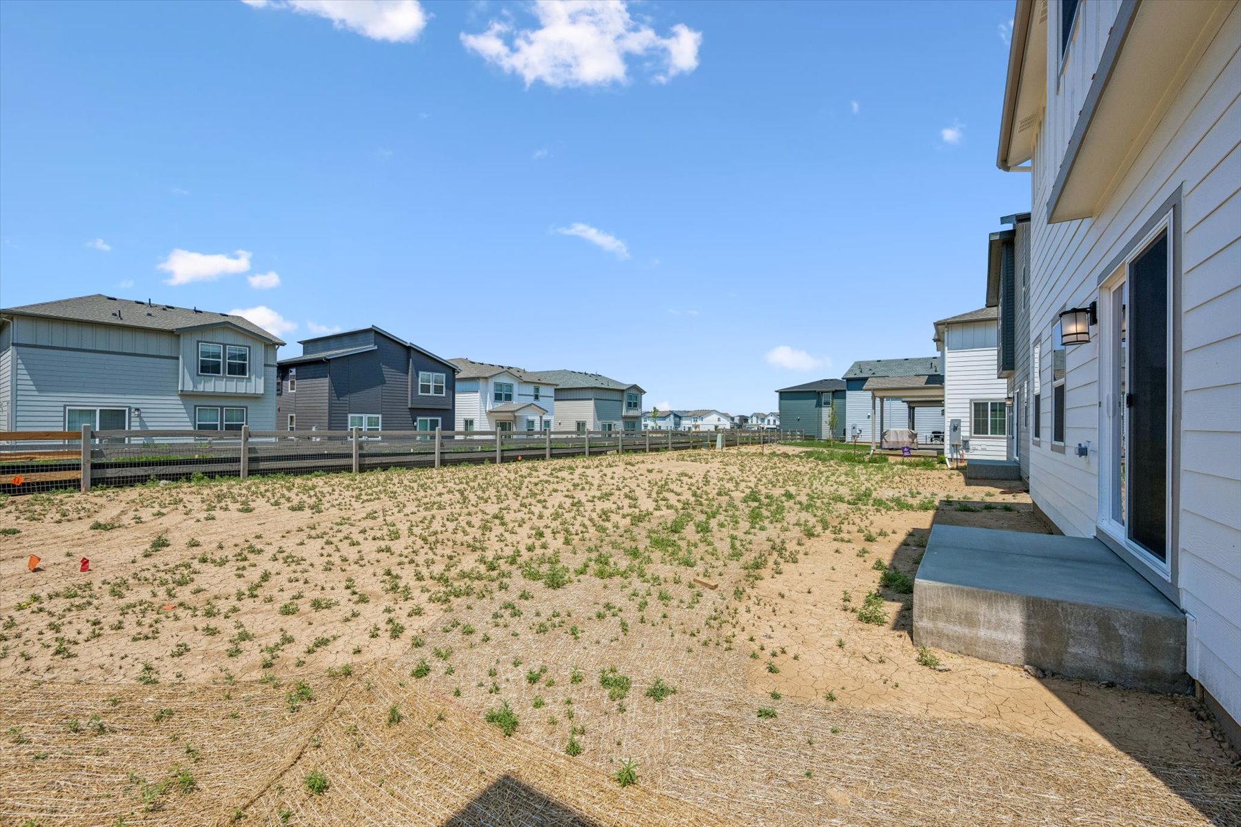 A dirt field with houses in the background.