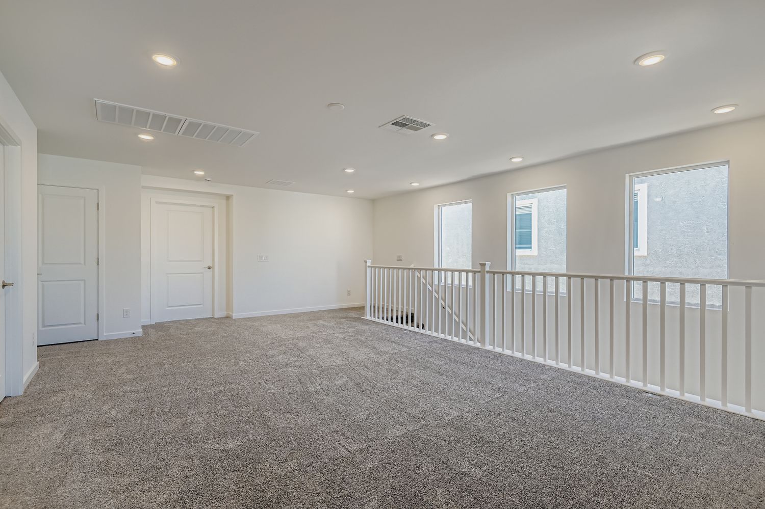 A room with white doors and a white railing.