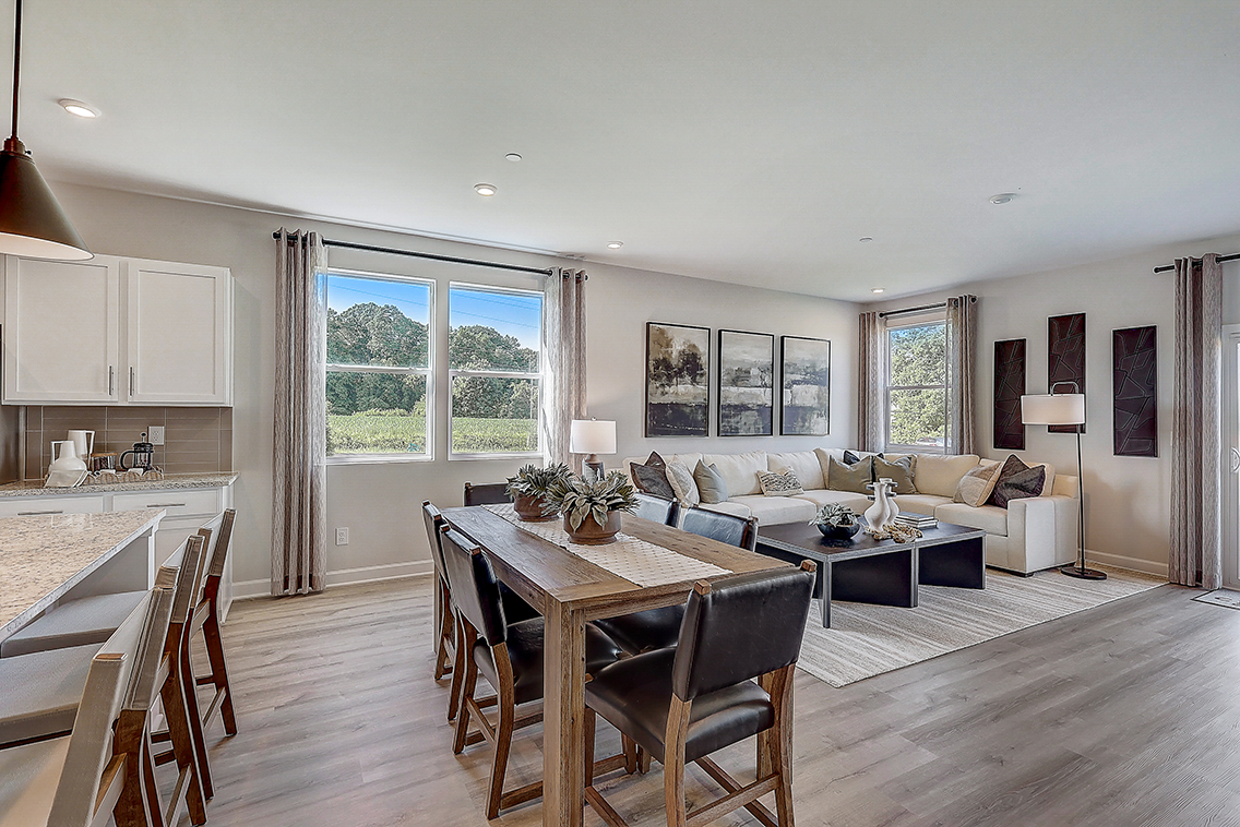 A large living room with a large dining table and a large window.