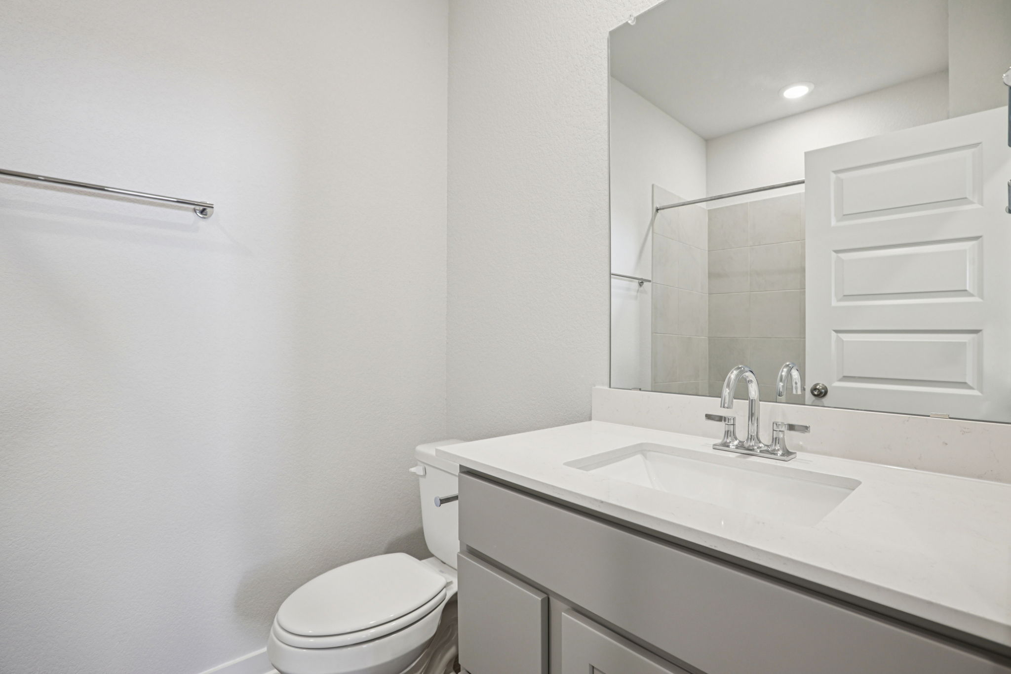 A bathroom with a sink toilet and mirror.