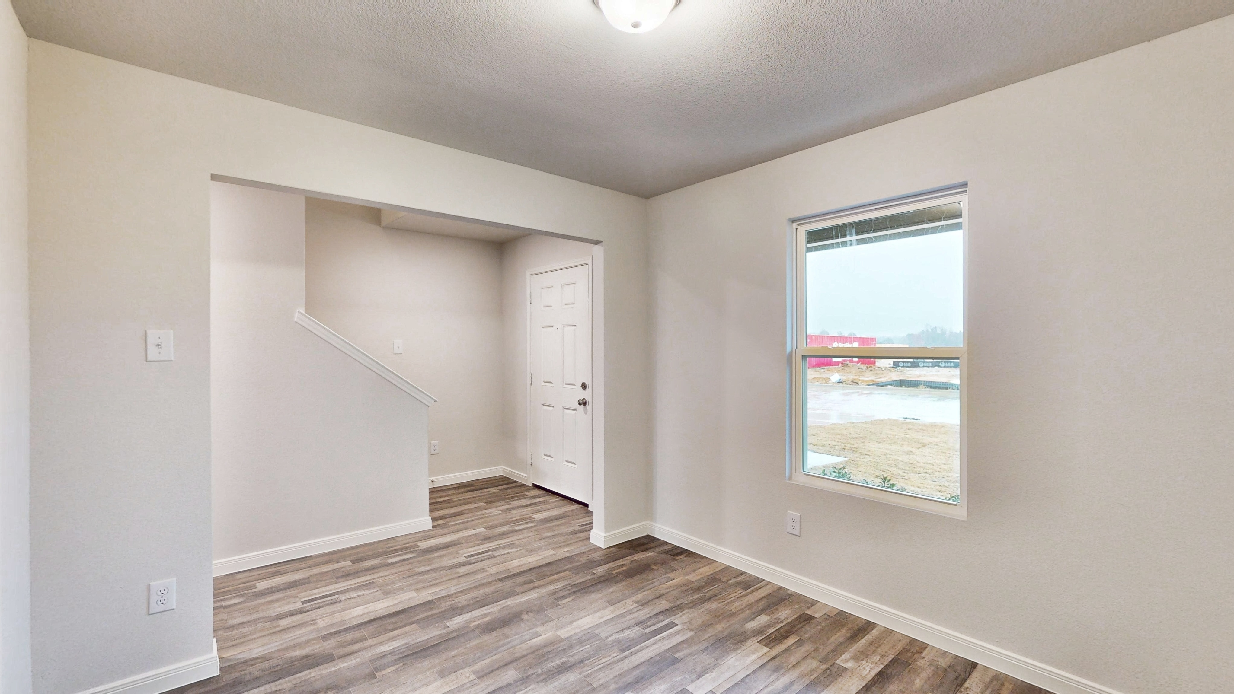 A room with a window and a wood floor.