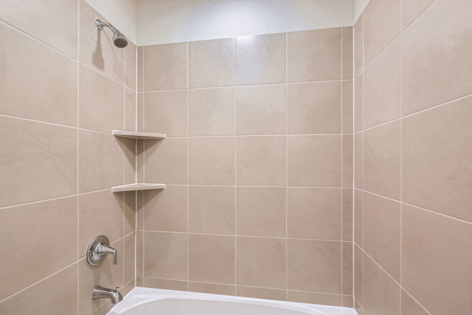 A bathroom with a bathtub and shelves.