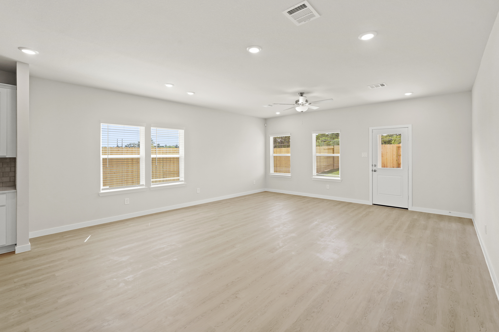 A large empty room with a wood floor and a white door.
