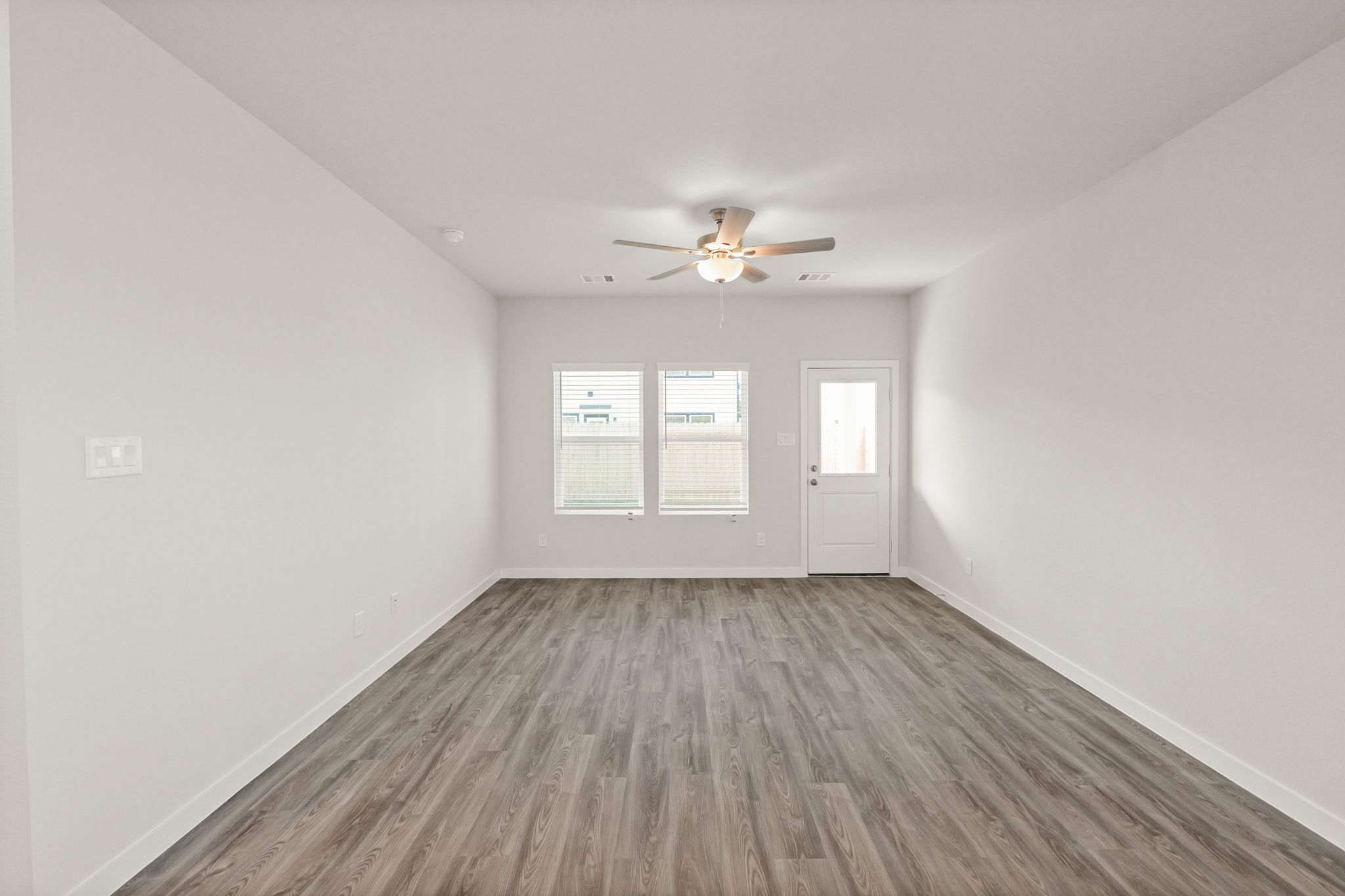 A room with a ceiling fan and a wood floor.