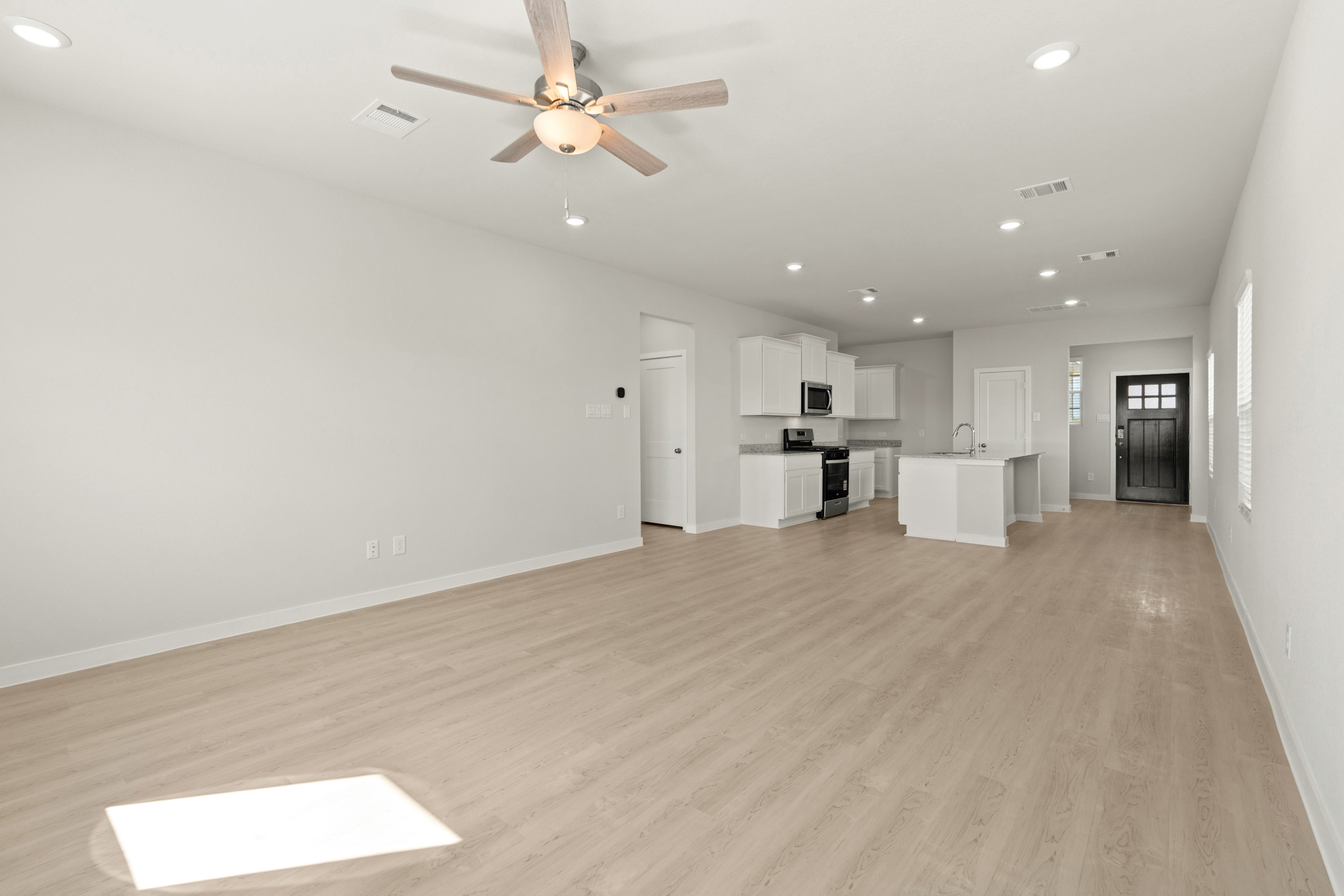 A large empty room with a ceiling fan and a wood floor.