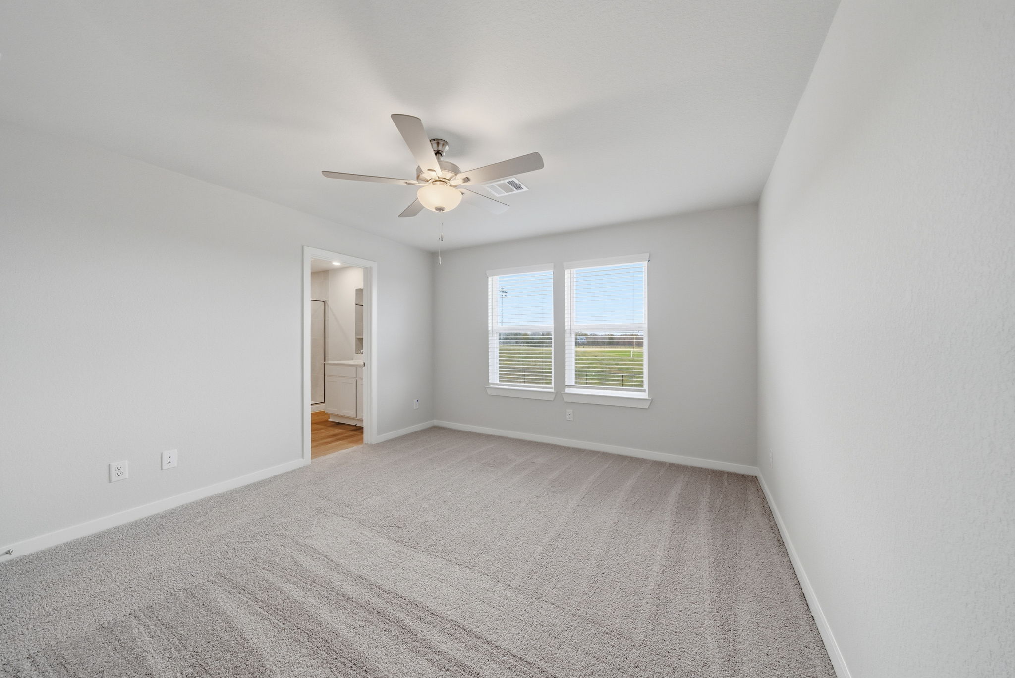 A room with a ceiling fan and a carpet.