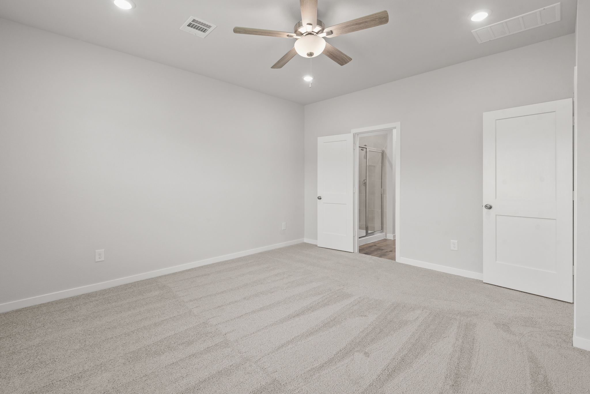 A room with a ceiling fan and a door.