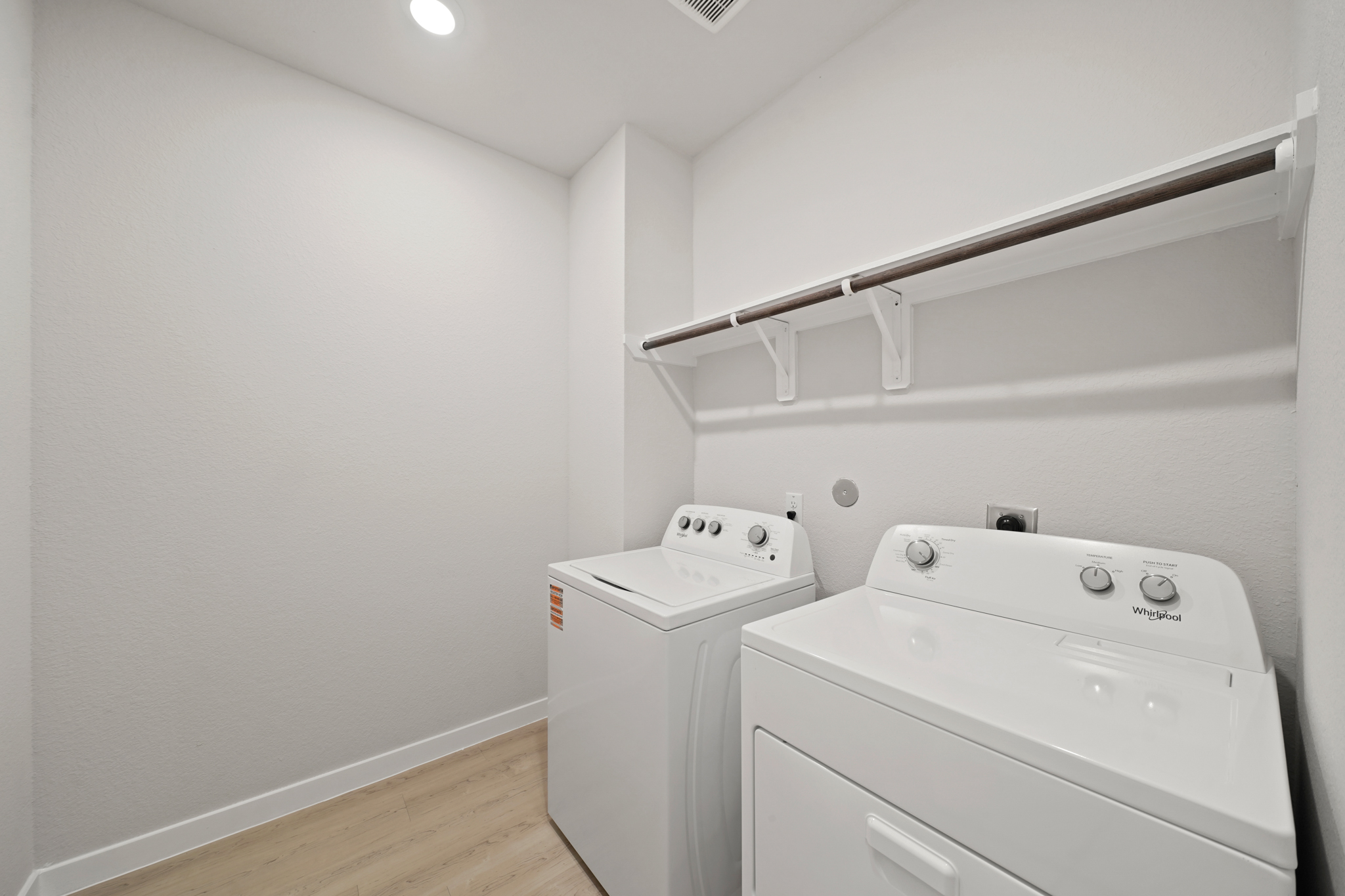 A white laundry room with a white shelf and white cabinets.