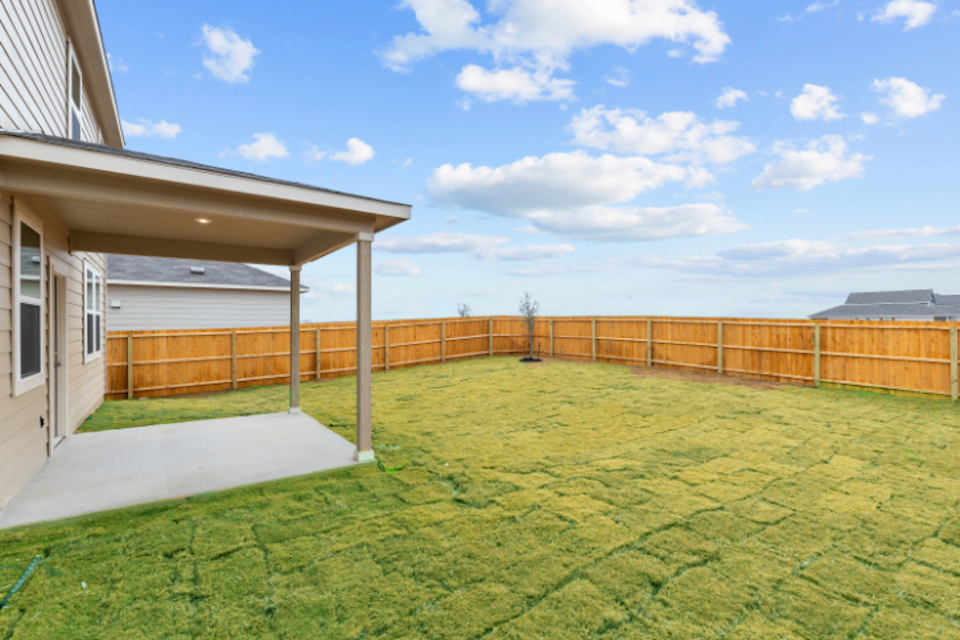 A backyard with a fence and grass.