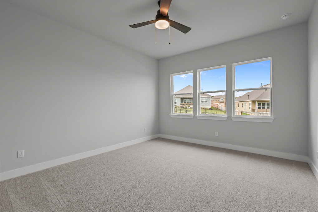 A room with a ceiling fan and a window with a view of the city.