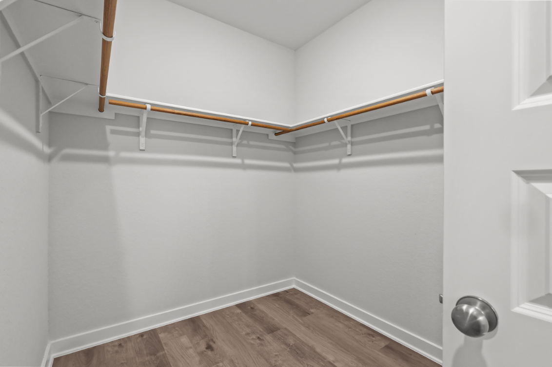 A white room with a wood floor and a metal bar.