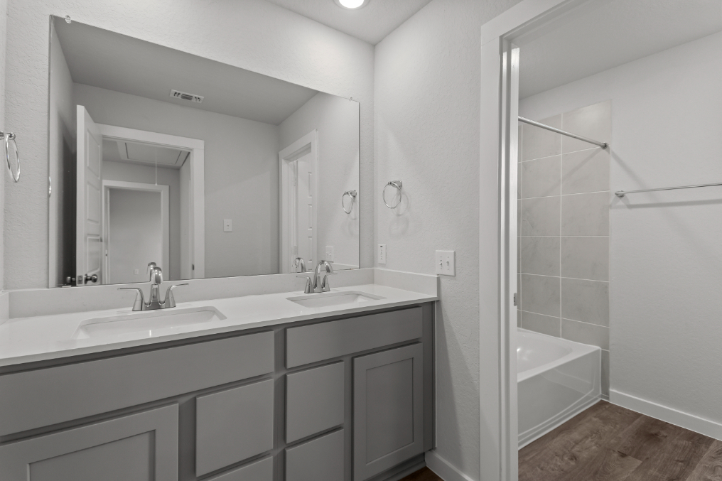 A bathroom with a tub sink and mirror.